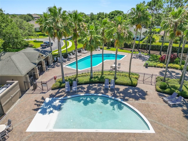 pool with a patio area and fence