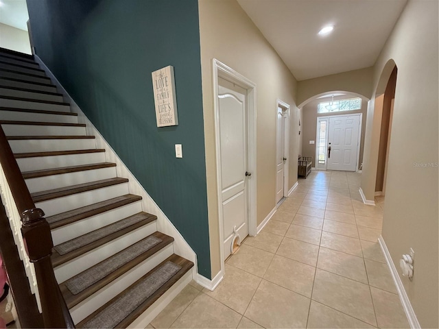 interior space with arched walkways, light tile patterned floors, recessed lighting, baseboards, and stairs