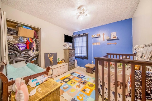 bedroom featuring carpet flooring, a crib, a closet, and a textured ceiling