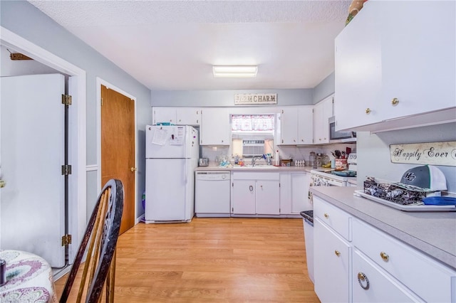 kitchen with light hardwood / wood-style flooring, white appliances, white cabinets, backsplash, and sink