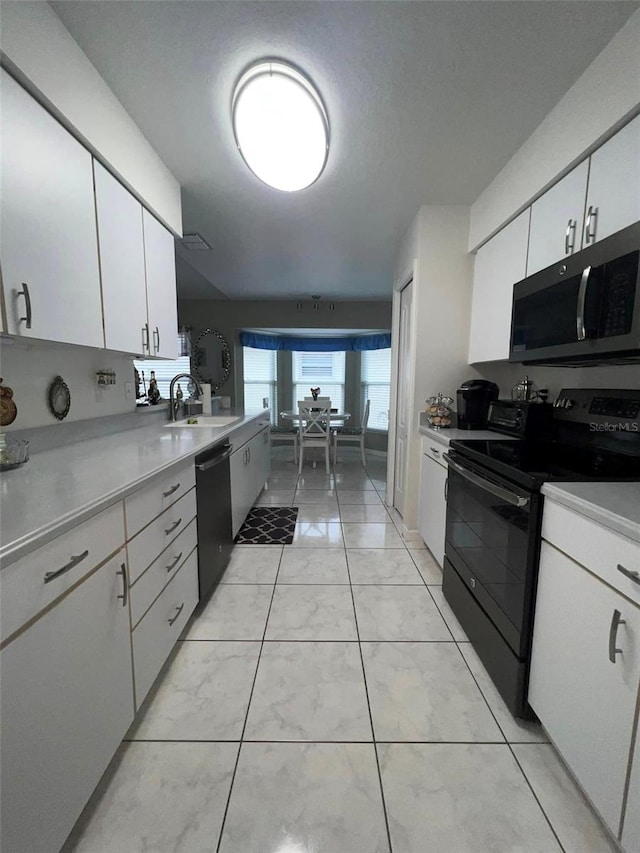 kitchen featuring white cabinetry, sink, light tile patterned flooring, and black appliances