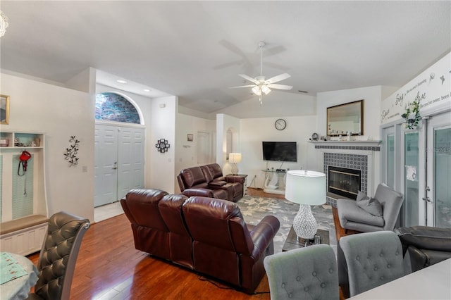 living room featuring a tiled fireplace, lofted ceiling, hardwood / wood-style floors, and ceiling fan