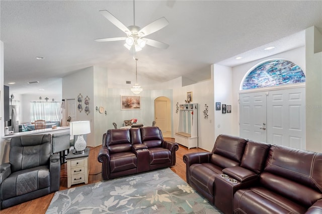 living room featuring ceiling fan, vaulted ceiling, a textured ceiling, and light hardwood / wood-style floors