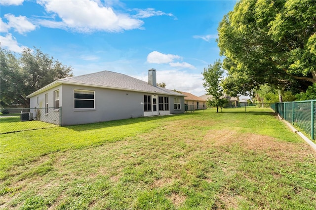 back of house featuring a yard and central AC