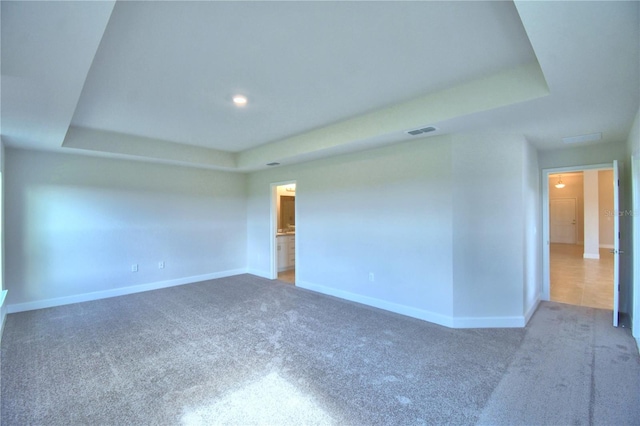 unfurnished room featuring carpet and a raised ceiling