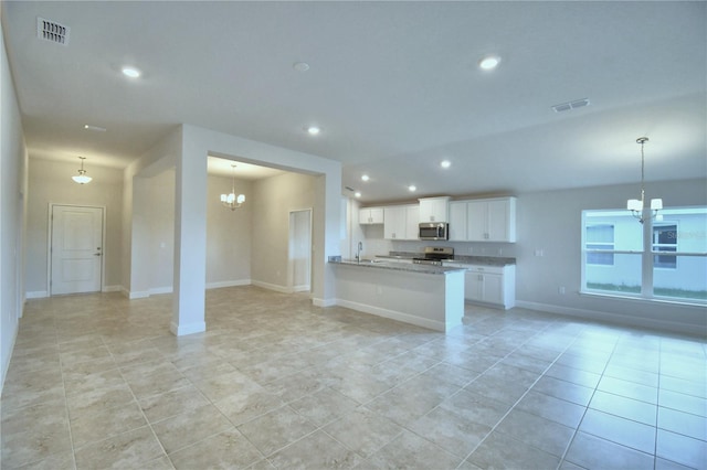 unfurnished living room featuring a notable chandelier, light tile patterned floors, and sink