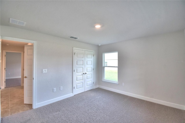 unfurnished bedroom with light carpet and a closet