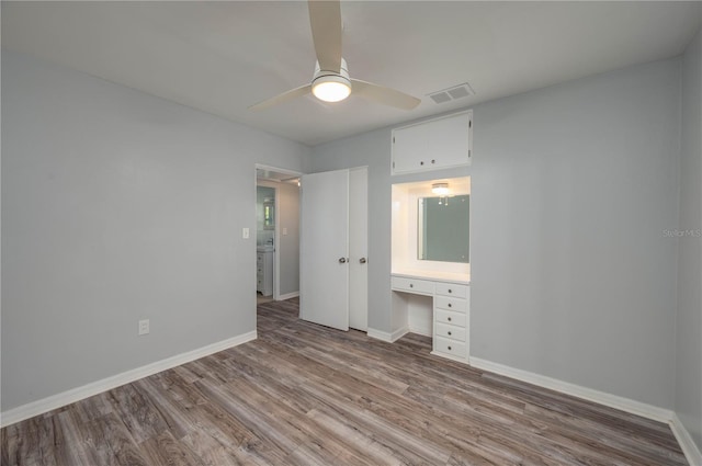 unfurnished bedroom featuring built in desk, ceiling fan, and light wood-type flooring