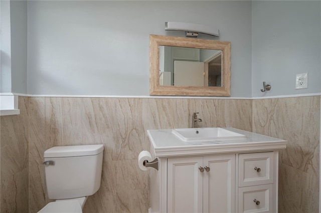 bathroom featuring vanity, toilet, and tile walls