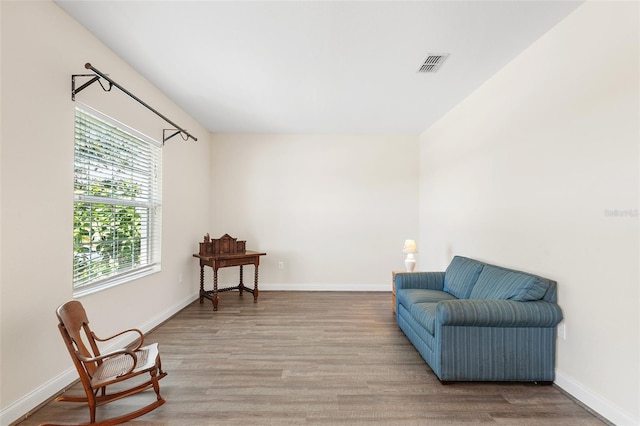 living area featuring baseboards, visible vents, and wood finished floors