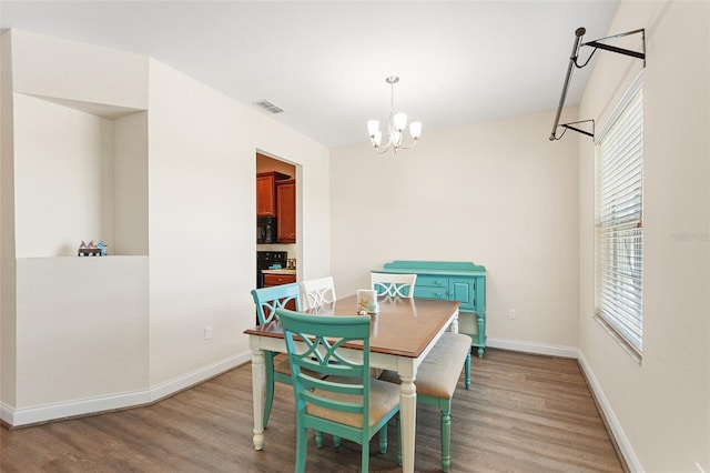 dining space featuring light wood-style floors, baseboards, visible vents, and an inviting chandelier