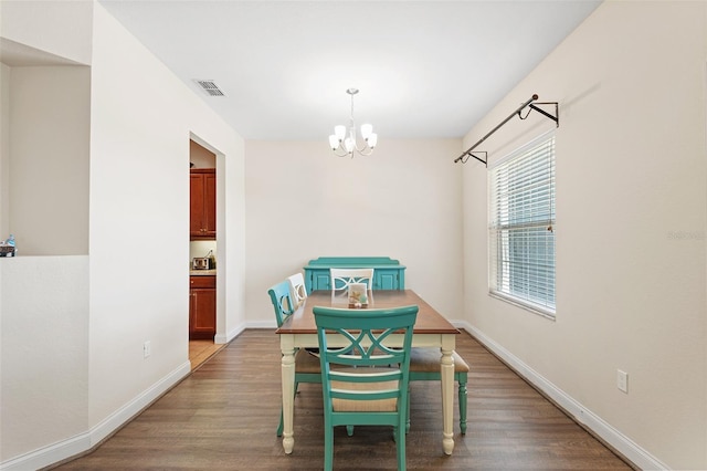 dining area featuring a chandelier, visible vents, baseboards, and wood finished floors