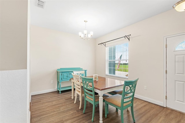 dining room with baseboards, visible vents, a chandelier, and wood finished floors