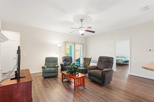 living room with a ceiling fan, wood finished floors, visible vents, and baseboards