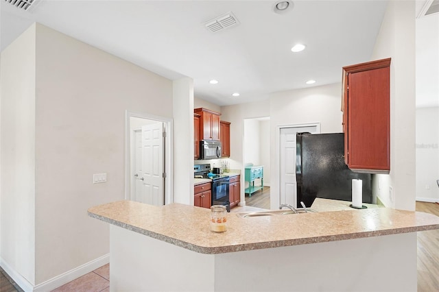 kitchen with a sink, visible vents, baseboards, light countertops, and black appliances