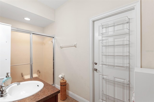 bathroom with a shower stall, vanity, and baseboards