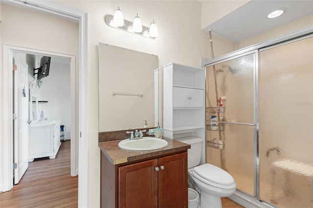 full bath with vanity, wood finished floors, a shower stall, and toilet