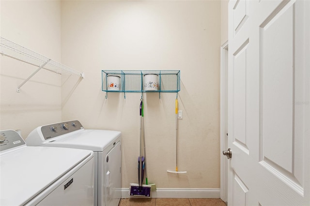 washroom featuring light tile patterned floors, laundry area, washer and clothes dryer, and baseboards