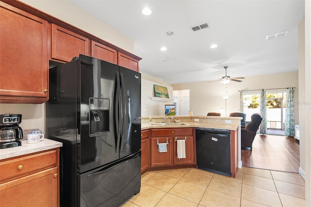 kitchen with a peninsula, a sink, open floor plan, light countertops, and black appliances