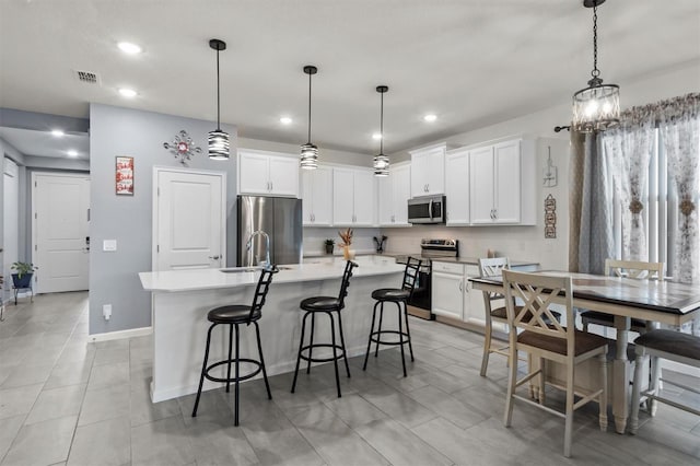 kitchen with stainless steel appliances, white cabinetry, hanging light fixtures, and a breakfast bar area