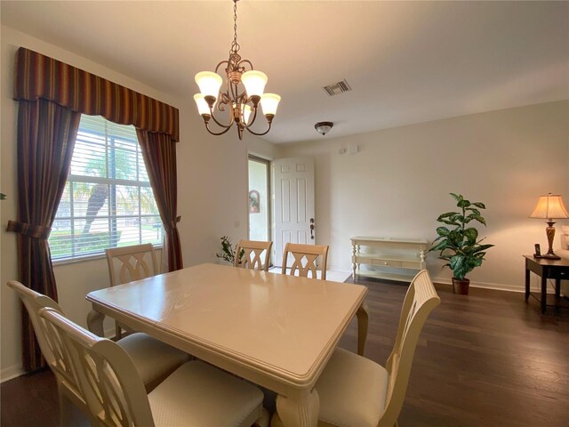 dining room with dark wood-type flooring and a chandelier