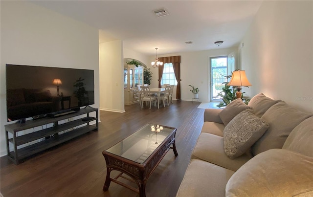 living room with a notable chandelier and dark wood-type flooring