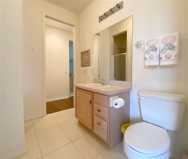 bathroom with toilet, vanity, tile patterned floors, and walk in shower