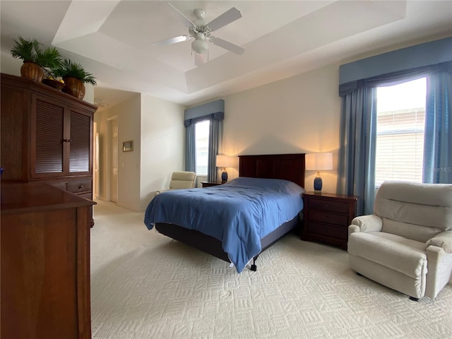 carpeted bedroom featuring a tray ceiling and ceiling fan