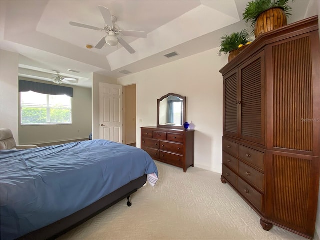 bedroom featuring light colored carpet, a raised ceiling, and ceiling fan