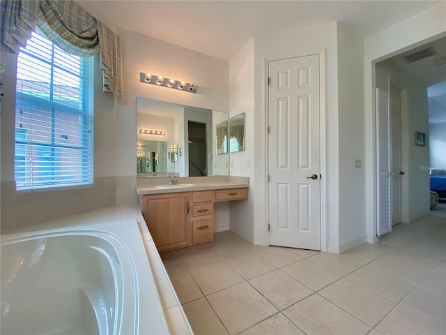 bathroom featuring tile patterned floors, tiled bath, and vanity