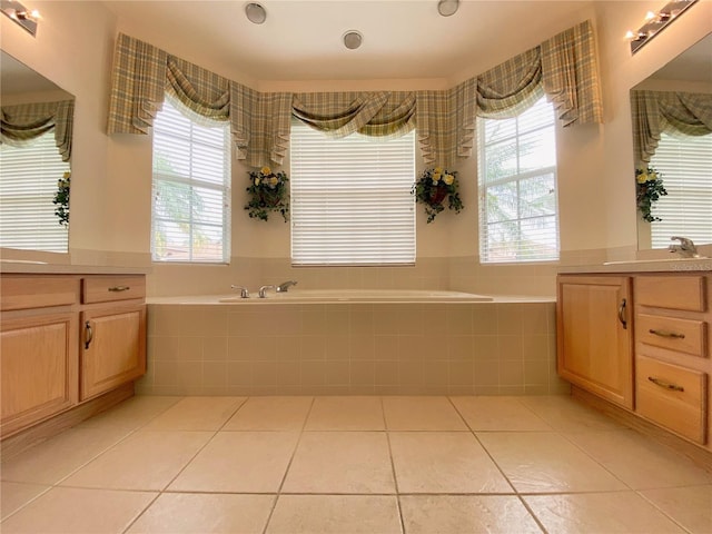 bathroom featuring tiled tub, vanity, and tile patterned flooring