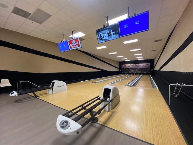recreation room with hardwood / wood-style flooring, a bowling alley, and a drop ceiling