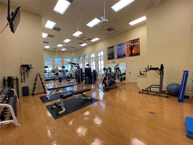 exercise room with hardwood / wood-style flooring, ceiling fan, and a high ceiling