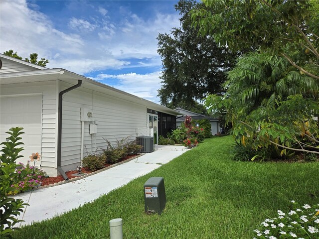 view of property exterior with a yard, a garage, and cooling unit