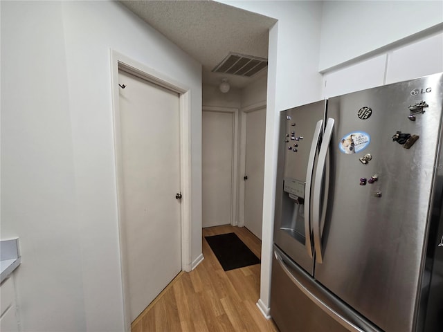 kitchen featuring stainless steel fridge with ice dispenser, white cabinets, and light wood-type flooring