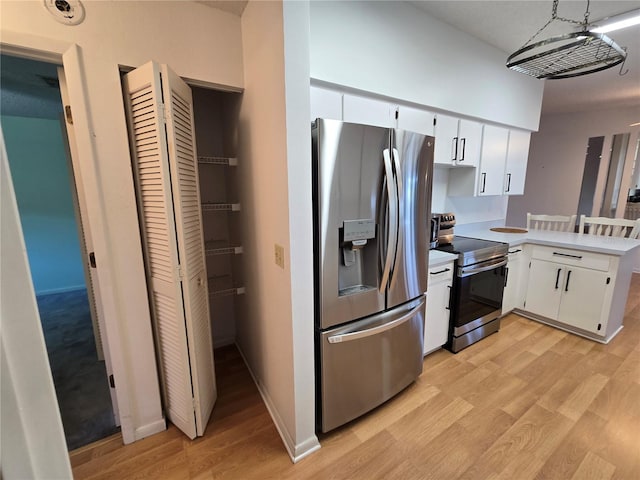 kitchen featuring white cabinetry, appliances with stainless steel finishes, light hardwood / wood-style floors, and pendant lighting