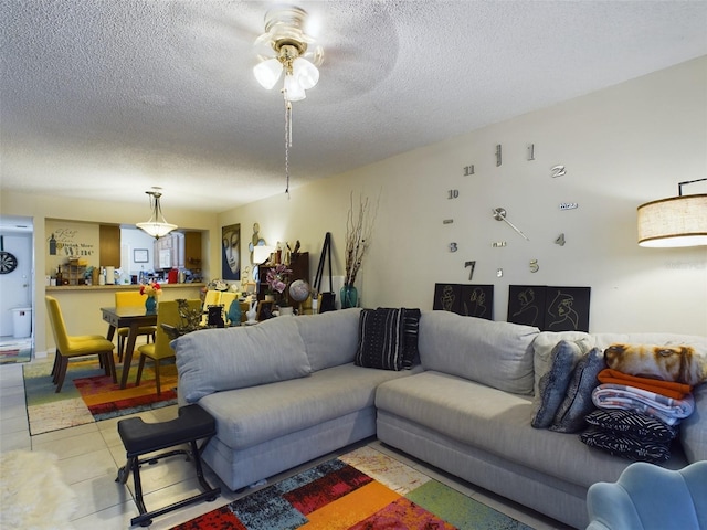 living room with a textured ceiling, ceiling fan, and tile patterned floors