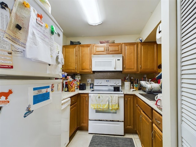 kitchen featuring tasteful backsplash, white appliances, and light tile patterned floors