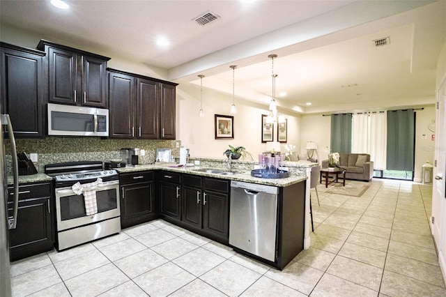 kitchen featuring kitchen peninsula, backsplash, hanging light fixtures, appliances with stainless steel finishes, and sink