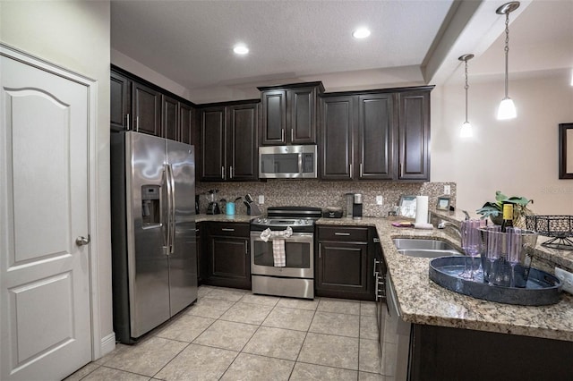 kitchen featuring light tile patterned flooring, backsplash, light stone countertops, appliances with stainless steel finishes, and sink