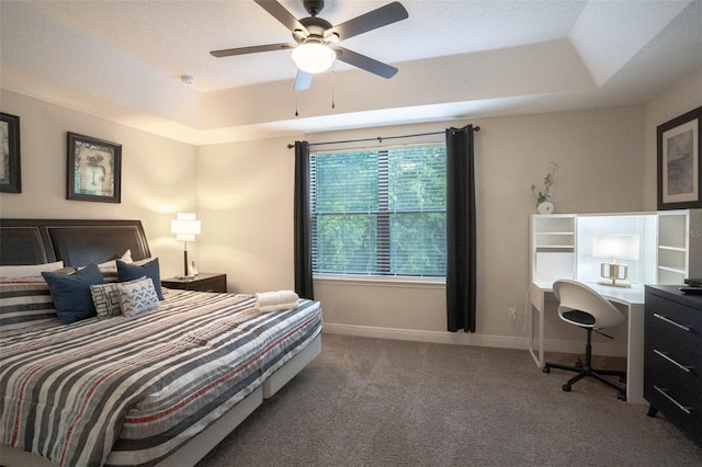 carpeted bedroom featuring ceiling fan and a raised ceiling