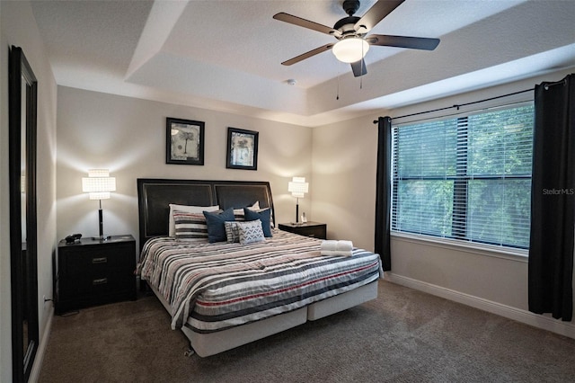 carpeted bedroom with ceiling fan and a tray ceiling