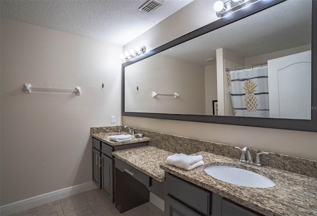 bathroom with a textured ceiling, tile patterned flooring, and double vanity