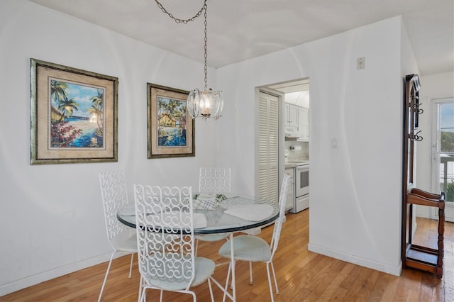 dining space with an inviting chandelier and light hardwood / wood-style flooring