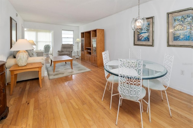 dining area with light hardwood / wood-style flooring and a notable chandelier