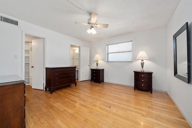 bedroom with ceiling fan, light wood-type flooring, a walk in closet, and a closet