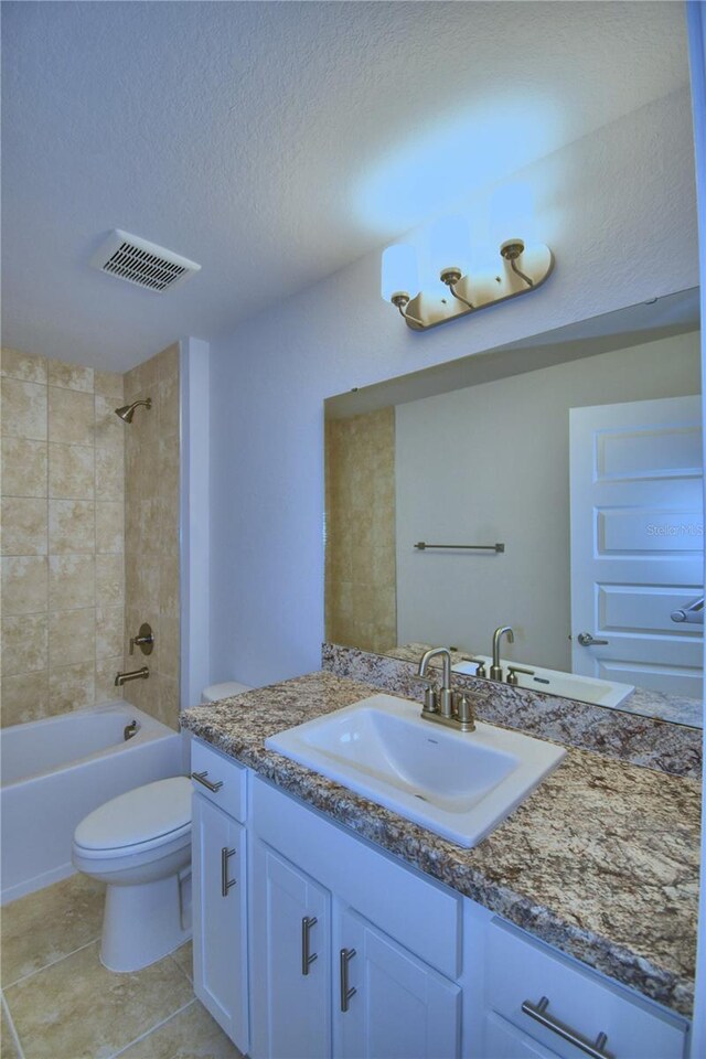 full bathroom with vanity, tile patterned floors, tiled shower / bath, and toilet