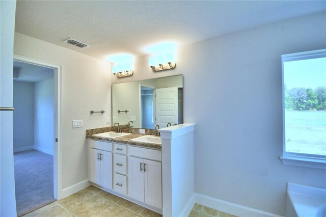 bathroom featuring tile patterned floors, a textured ceiling, and double sink vanity