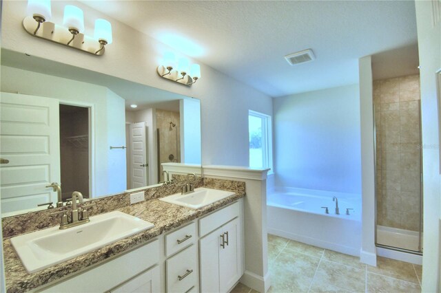 bathroom featuring plus walk in shower, a textured ceiling, tile patterned flooring, and dual bowl vanity