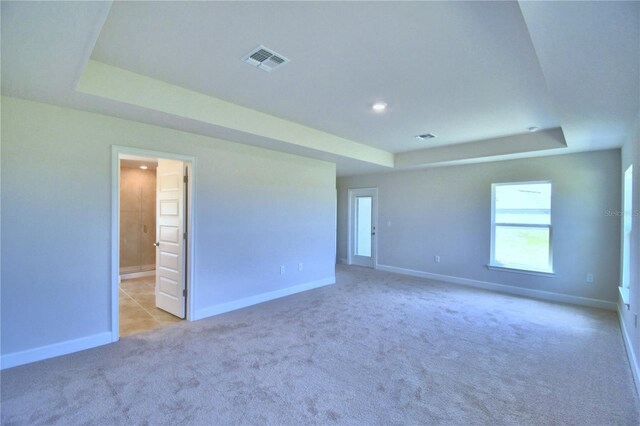 carpeted empty room featuring a raised ceiling